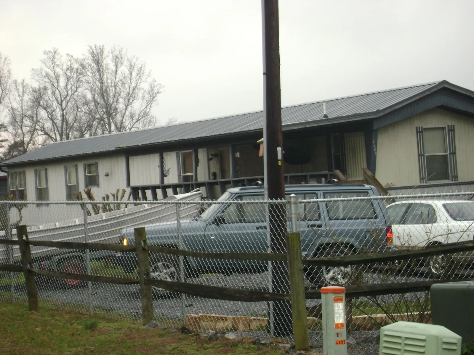 Dark metal roof on a long single story building behind a chain link fence in Cashion